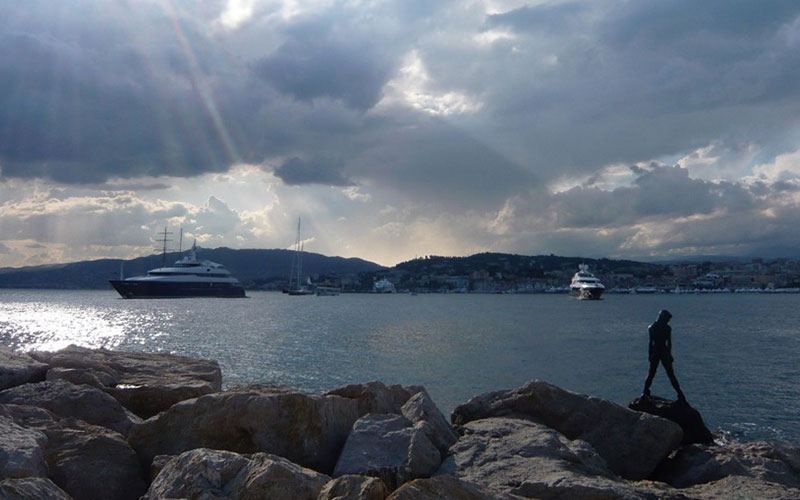 Rocks in front of the water with big boats on